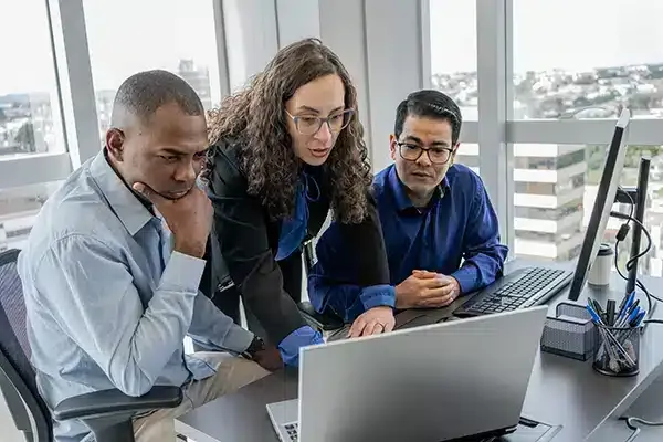 woman training two male employees in an IT office.